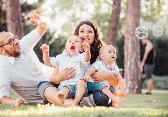 Joyful family enjoying a sunny day in the park while playing with bubbles.