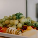 A vibrant assortment of fruits including grapes, apples, and berries on a white tray.