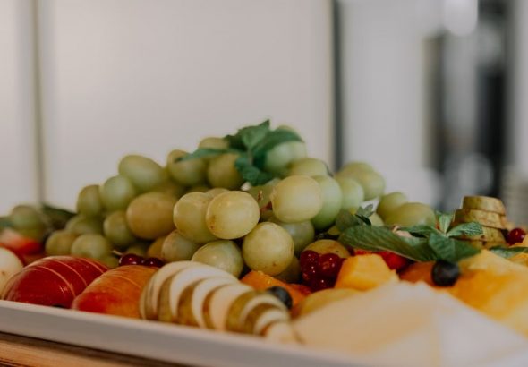 A vibrant assortment of fruits including grapes, apples, and berries on a white tray.
