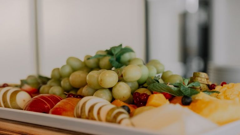 A vibrant assortment of fruits including grapes, apples, and berries on a white tray.